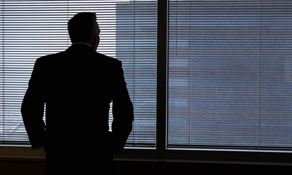 man looking out a office window.